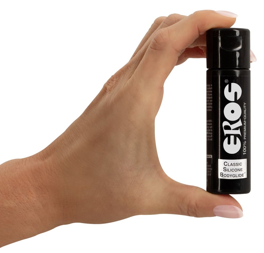 Hand die een kleine zwarte fles EROS Classic Silicone Bodyglide vasthoudt.