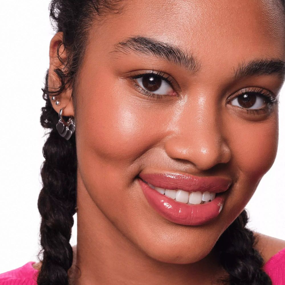 Portrait d'une femme avec du rouge à lèvres rose. Elle sourit. Teint foncé.