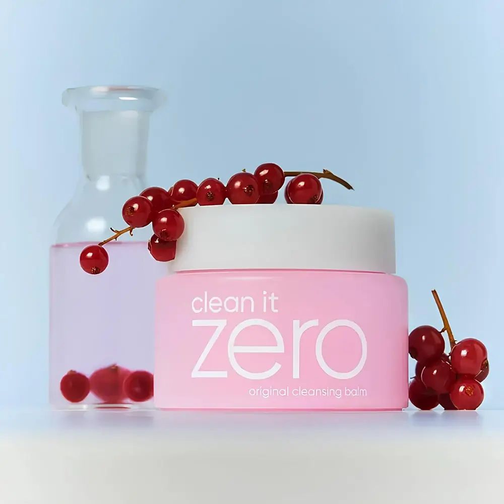 Roze pot met witte deksel. Opschrift "clean it zero original cleansing balm". Daarnaast een glazen fles en rode bessen.