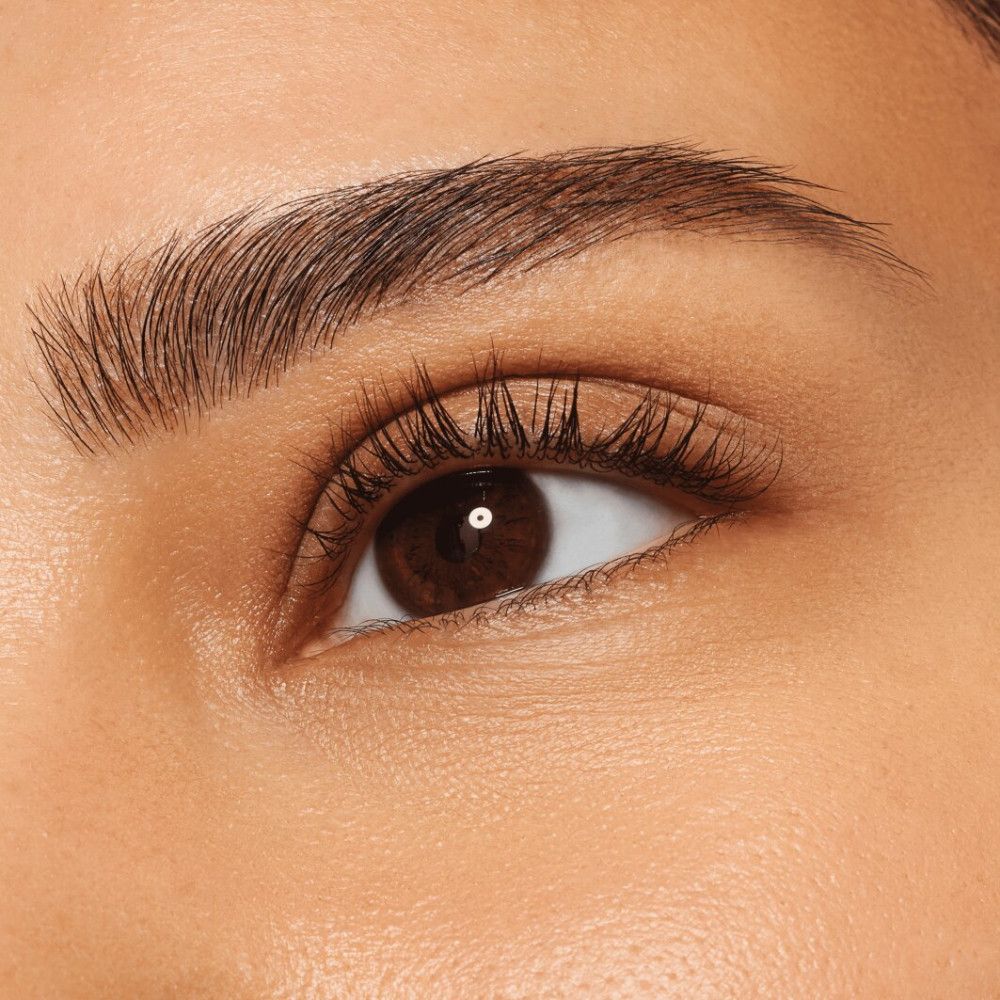 Close-up van een oog met gevormde wenkbrauwen. De wenkbrauw is donkerbruin en goed gedefinieerd.