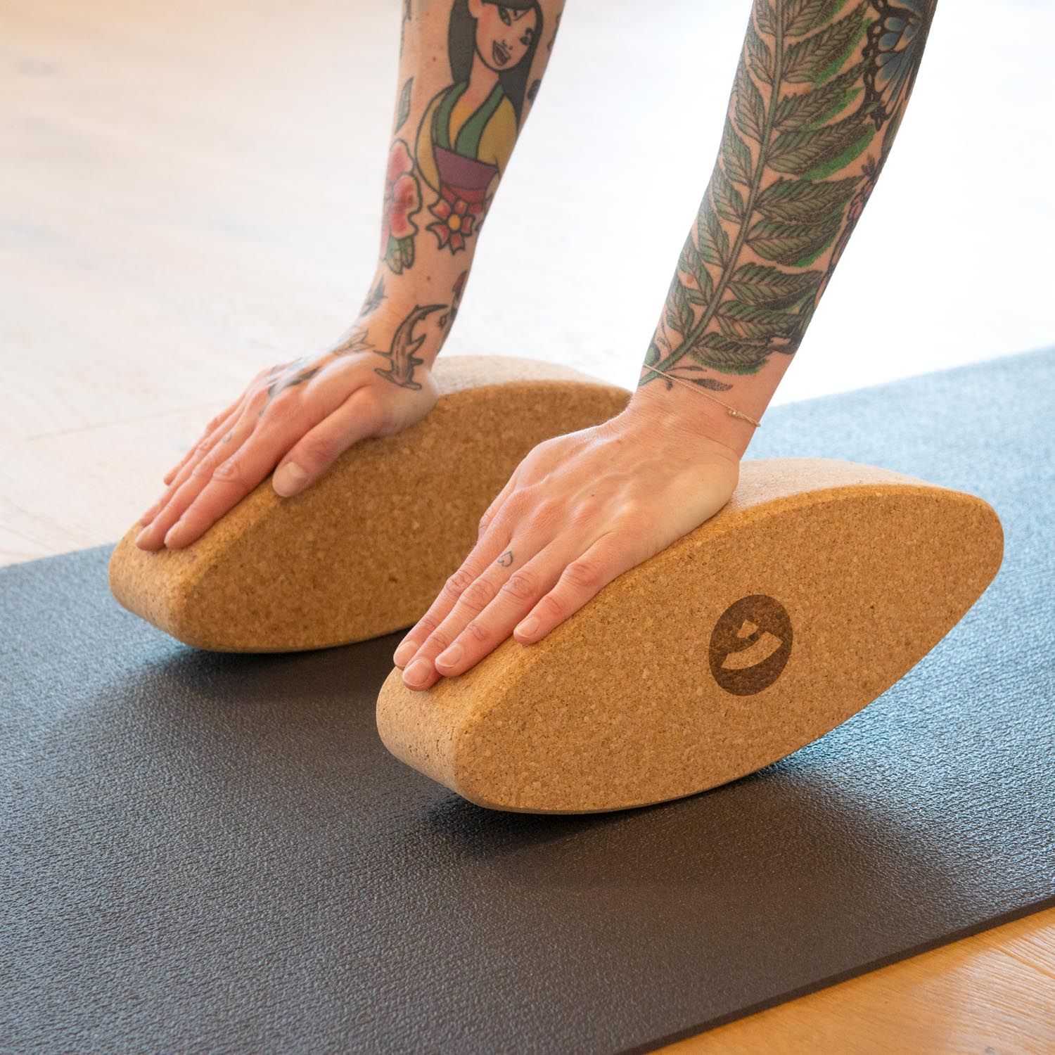Deux ellipses en liège sur tapis de yoga. Mains sur les ellipses. Bras tatoués.