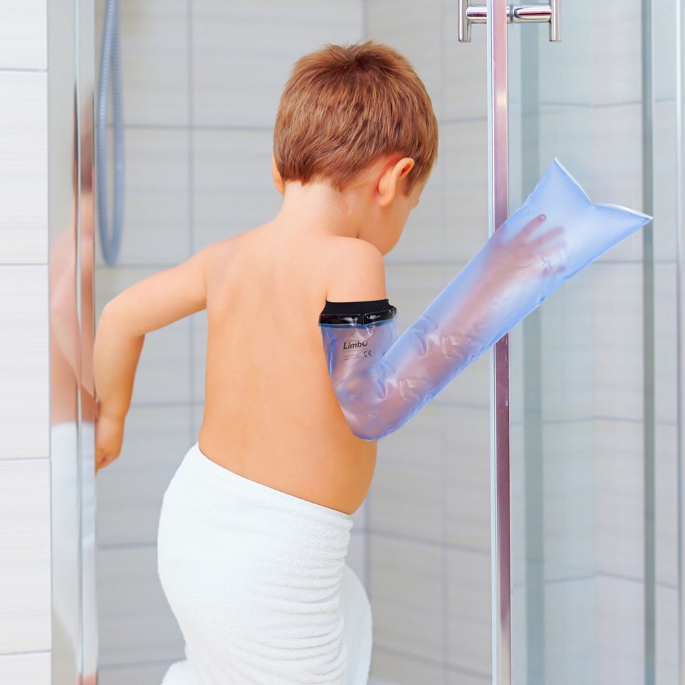 Enfant avec protection de bras pour plâtre dans une douche. Matériau bleu transparent. Bord noir au bras.