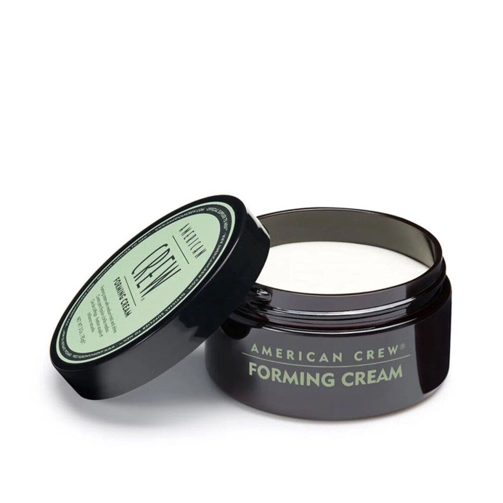 Pot brun foncé ouvert avec contenu blanc. Couvercle à côté. Inscription: AMERICAN CREW FORMING CREAM.