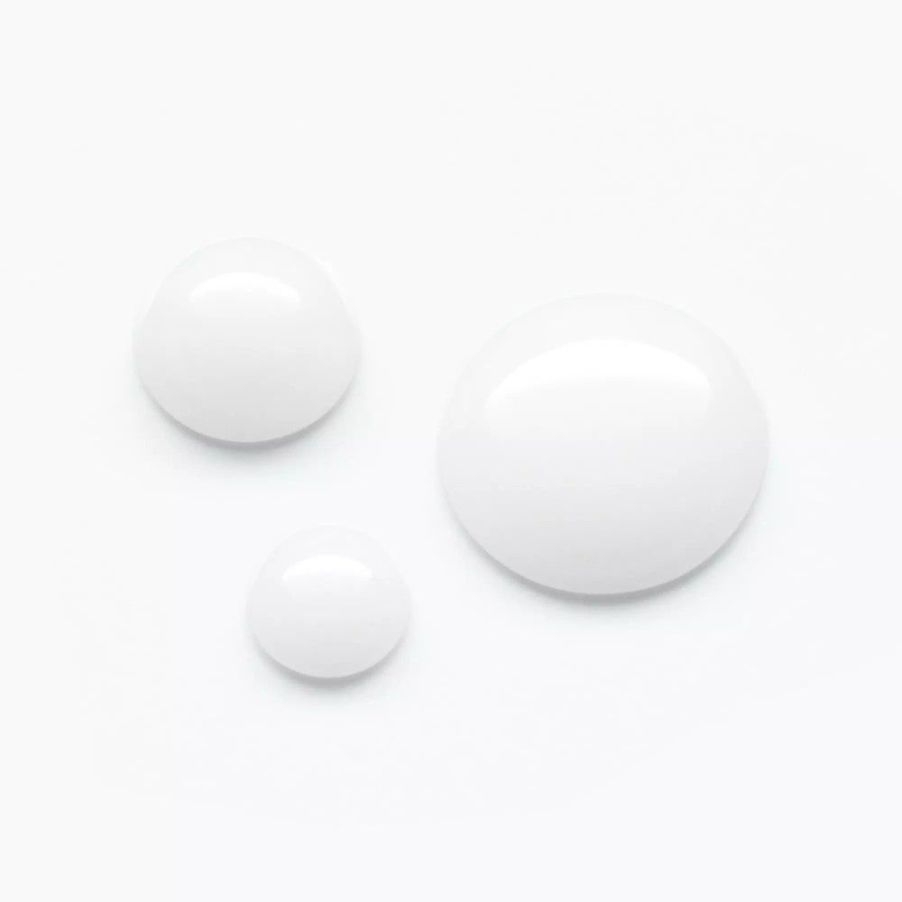 Trois gouttes blanches, probablement du sérum. Différentes tailles, sur fond blanc. Pas d'emballage ni de nom de marque visibles.