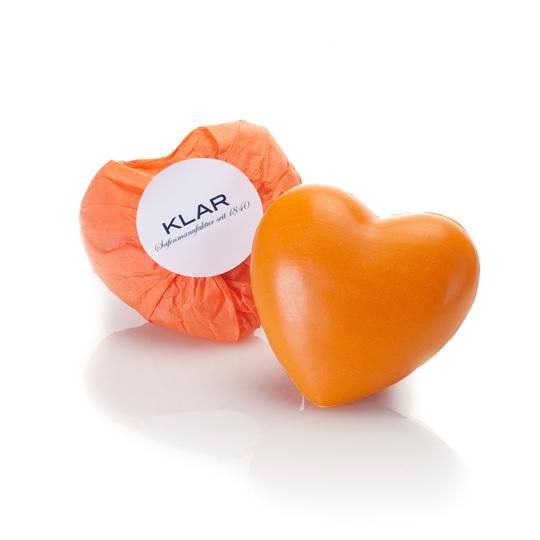 Savon orange en forme de cœur. À côté, savon emballé avec une étiquette blanche portant le logo Klar.