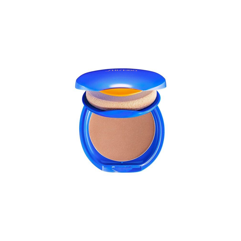 Boîtier compact bleu ouvert. Contient une éponge et une poudre brune. "Shiseido" est écrit en haut.