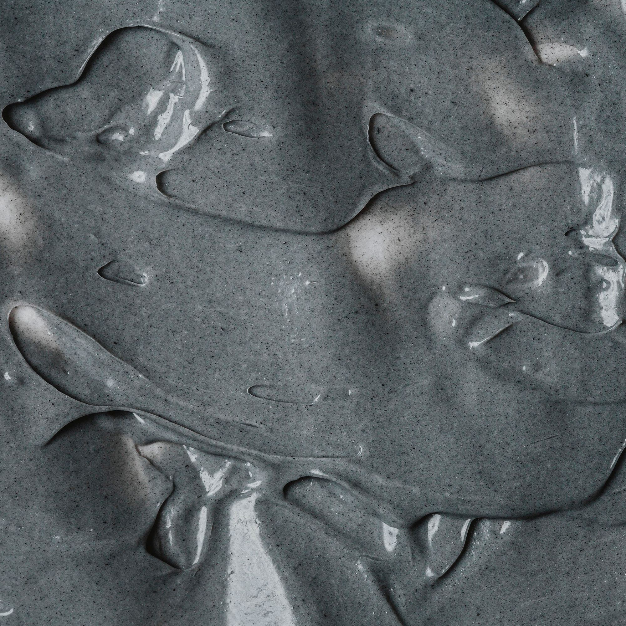 Close-up van een grijs gezichtsmasker. Romige textuur met onregelmatige vormen.