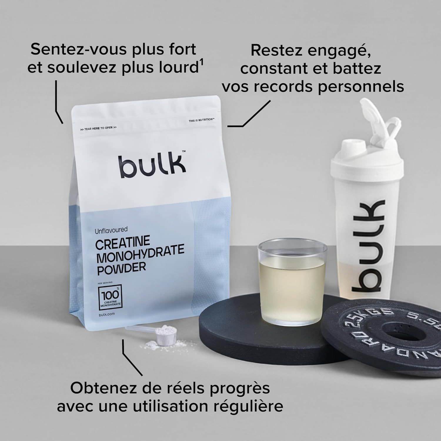 Sachet de poudre de créatine monohydrate Bulk, shaker blanc, verre de liquide et disques d'haltérophilie.