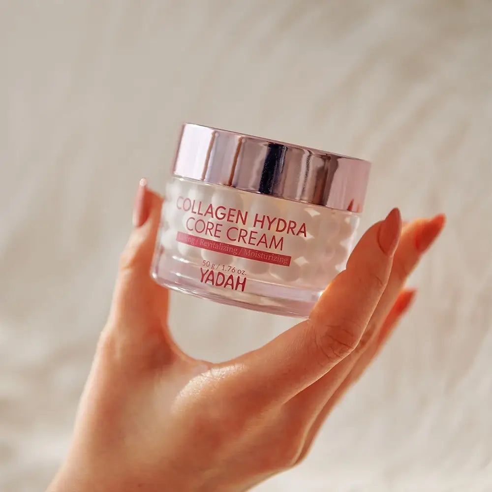 Pot en verre avec couvercle rose. Inscription: Collagen Hydra Core Creme. Marque: YADAH. Main tenant la crème.