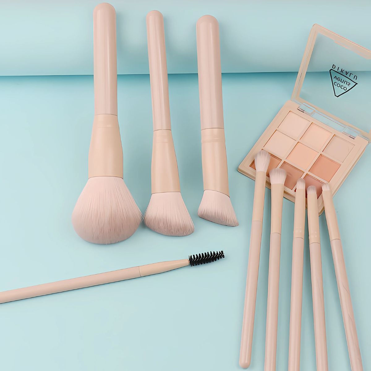 Un ensemble de quatre pinceaux de maquillage beige clair et une palette de fard à paupières de huit couleurs.