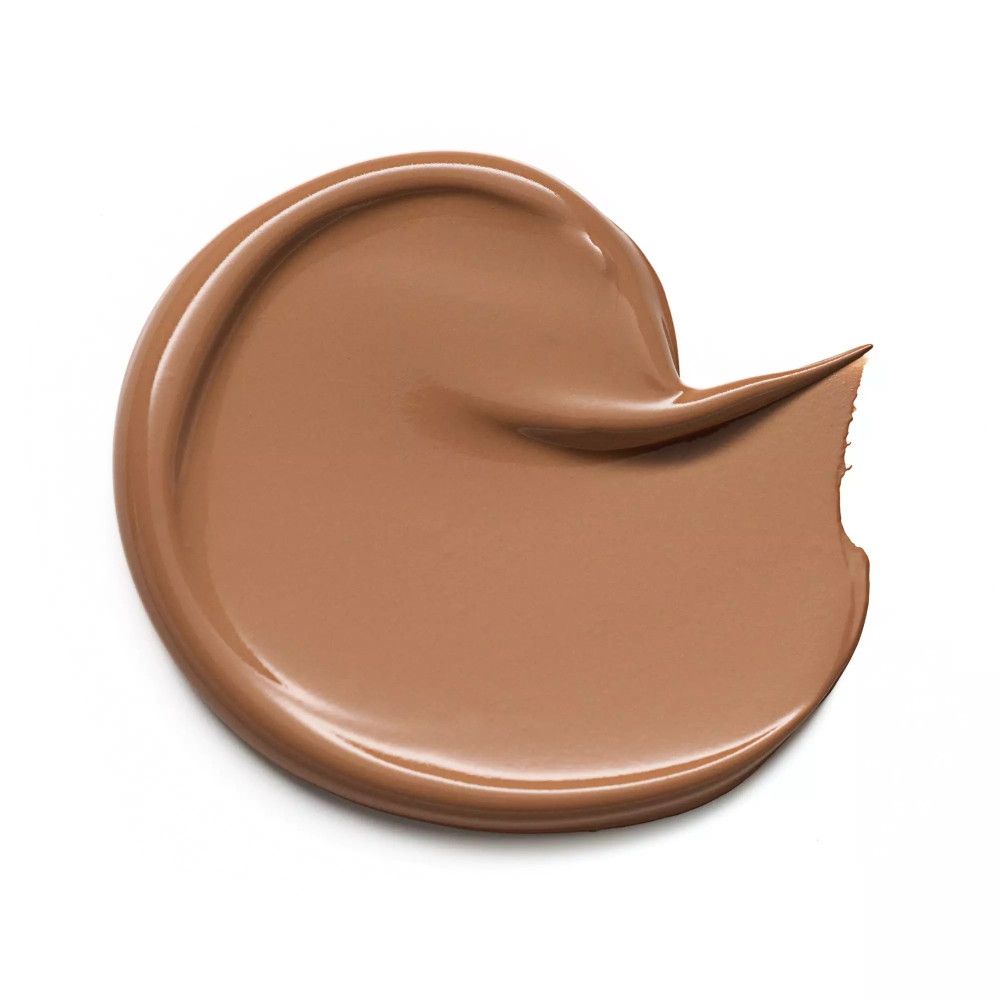 Tache de correcteur brun étalée sur fond blanc. La texture est lisse et mate.