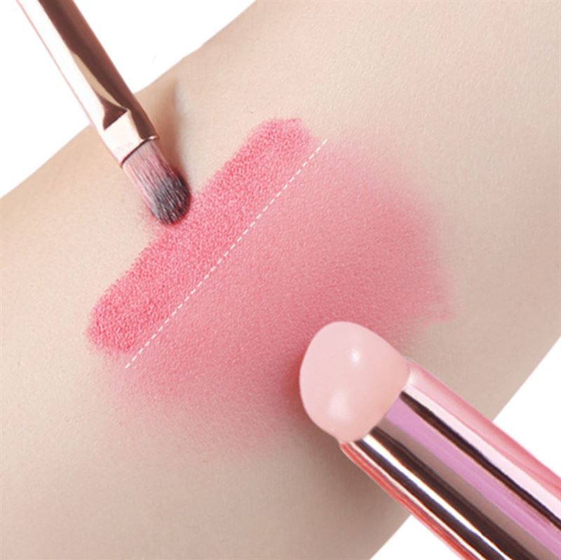 Deux pinceaux sur la peau. L'un applique un produit rose. L'autre est à proximité.