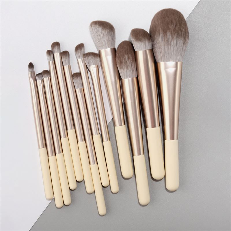 Ensemble de pinceaux de maquillage. 12 pinceaux avec manches crème, viroles argentées et différentes têtes.