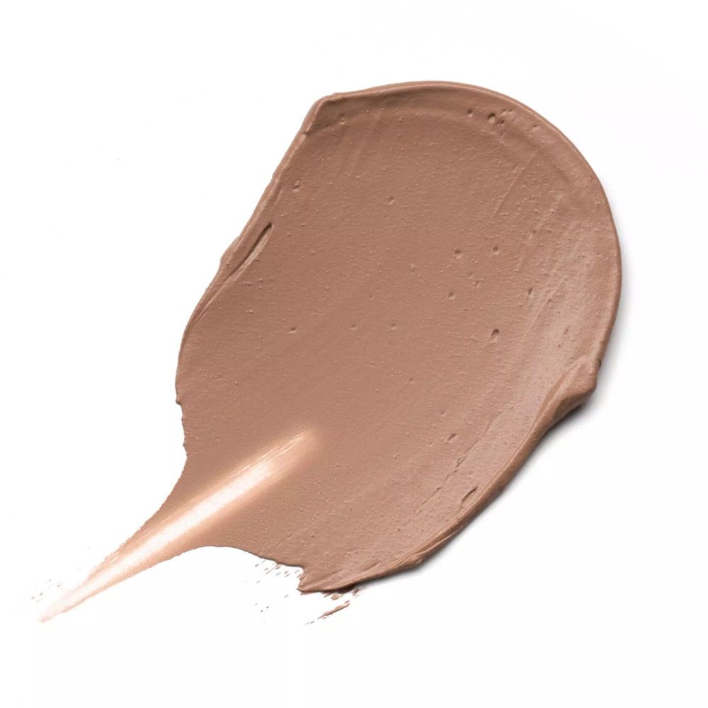 Tache de fond de teint brun clair sur fond blanc. Texture visible.