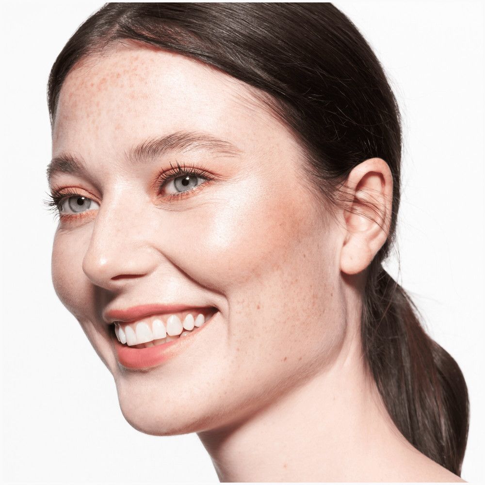 Portret van een vrouw met roze lippenstift. Ze glimlacht. Lichte huid, donker haar.