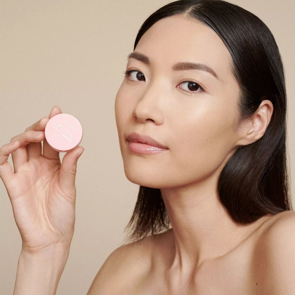 Femme asiatique tenant un pot rose. Sur le pot, "CATRICE LIP LOVIN' OVERNIGHT LIP MASK".