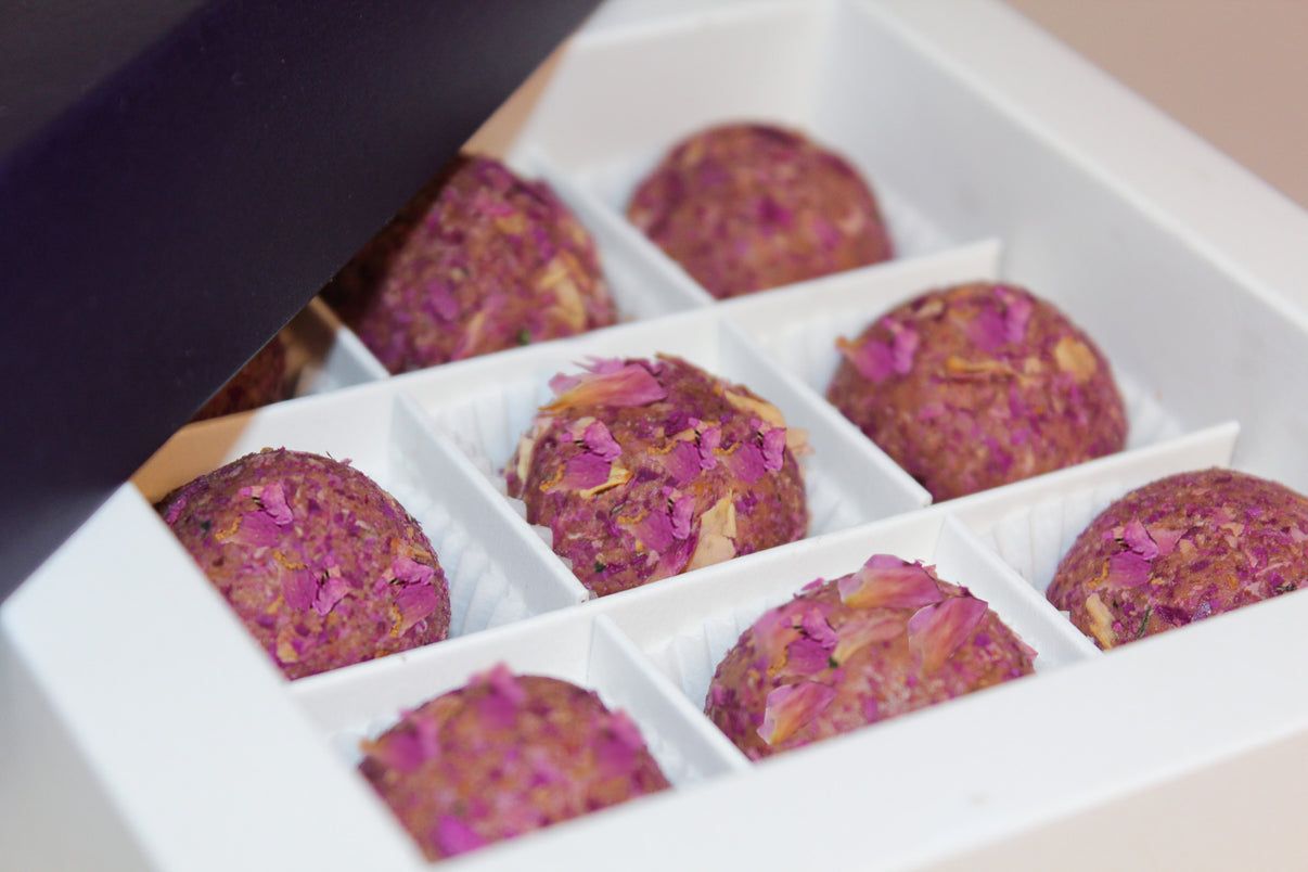 Boîte de neuf truffes rondes, recouvertes de pétales de rose.