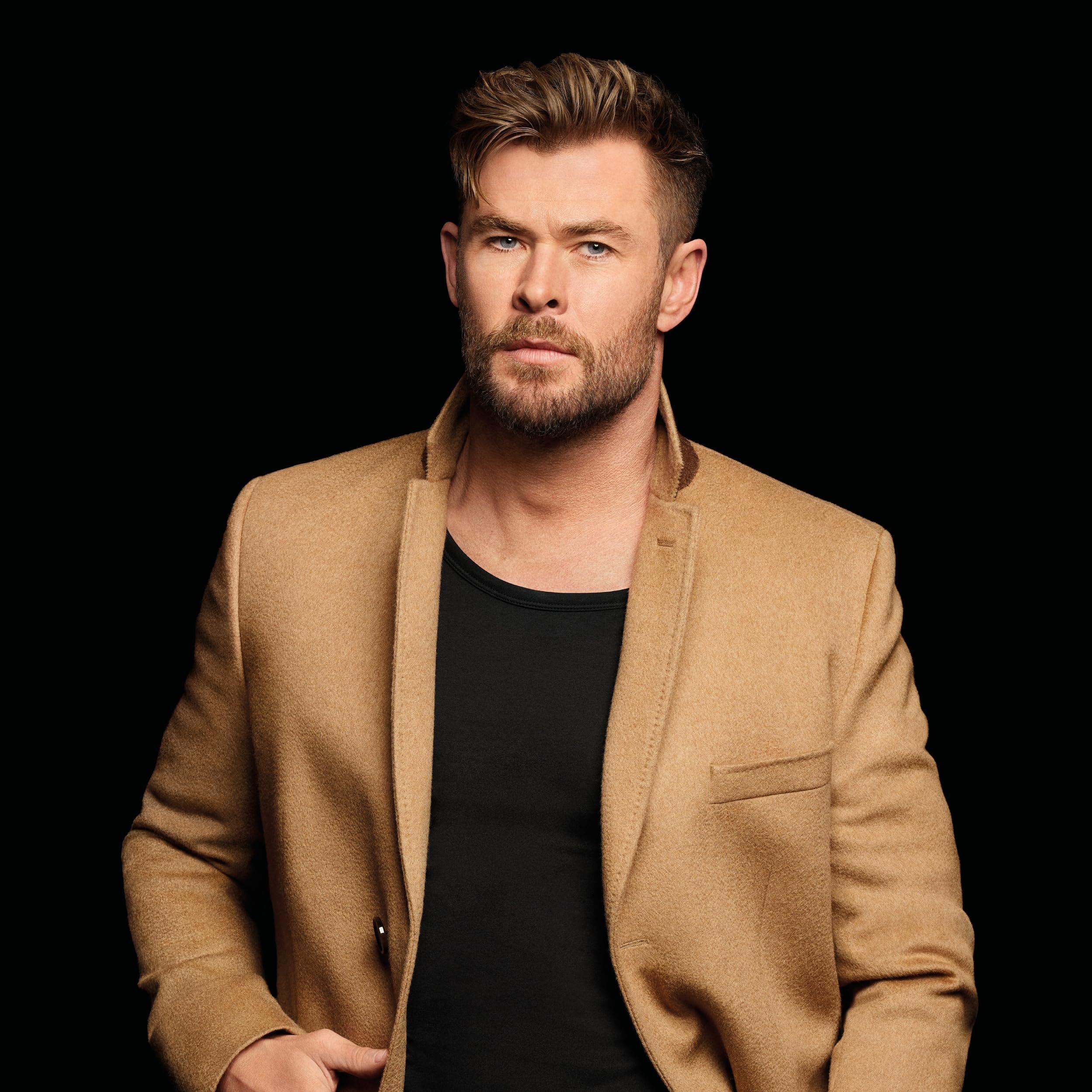 Homme en veste beige et t-shirt noir, regardant sérieusement.