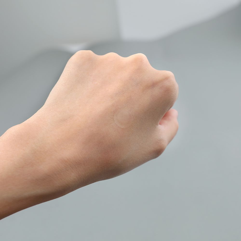 Gesloten hand met een kleine, ronde pleister op de huid.