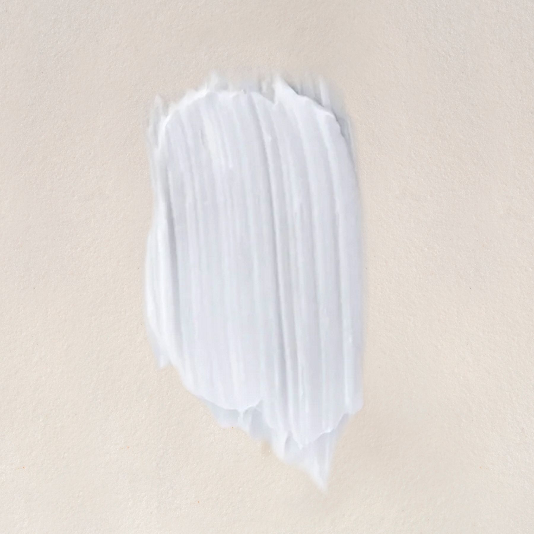 Une épaisse traînée de baume blanc avec des marques de spatule visibles sur une surface claire.