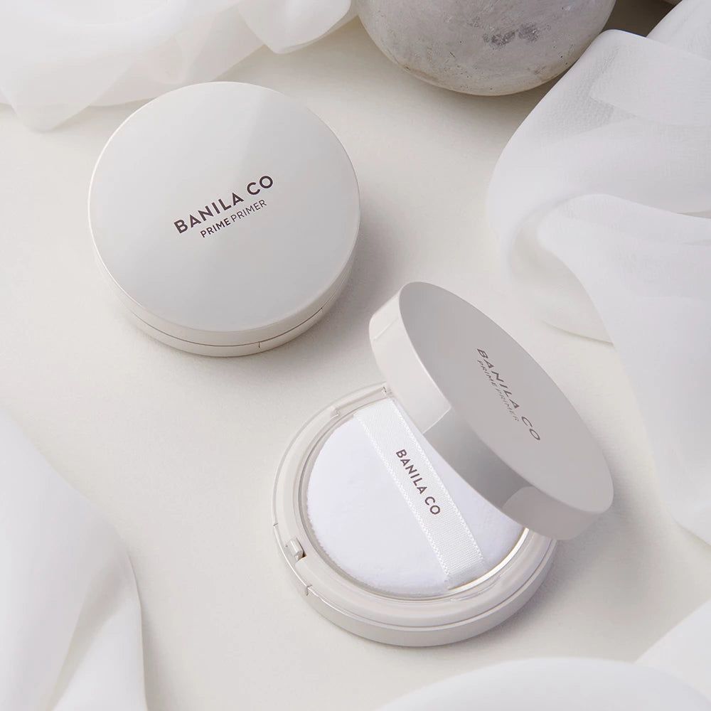 Witte ronde compacte verpakking met Banila Co Prime Primer opschrift. Open verpakking toont applicator.