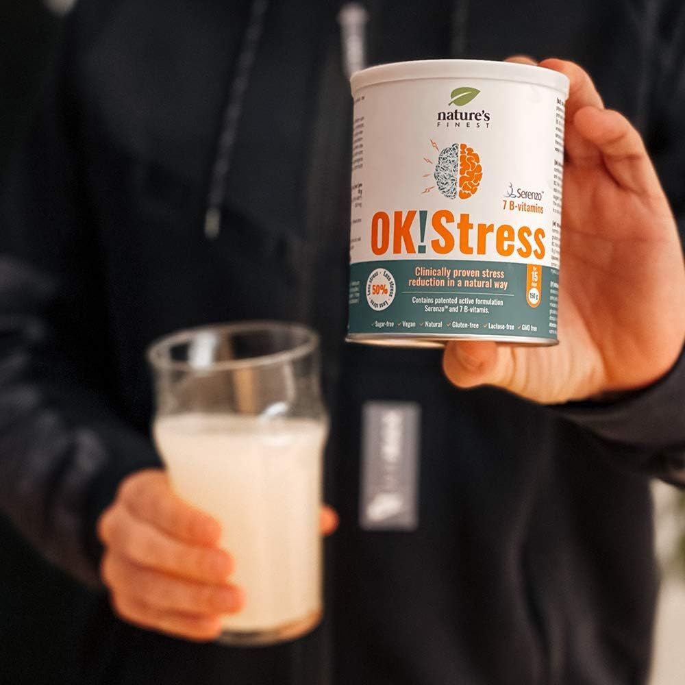 Personne tenant une boîte OK!Stress et un verre. Inscriptions : Nature's Finest, OK!Stress, 7 vitamines B. Réduction du stress cliniquement prouvée.