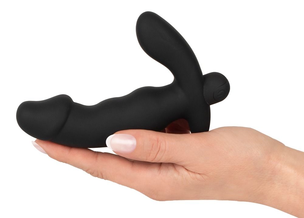 Zwarte, cock-vormige buttplug met vibratie. In hand gehouden. Gebogen vorm, knop zichtbaar.