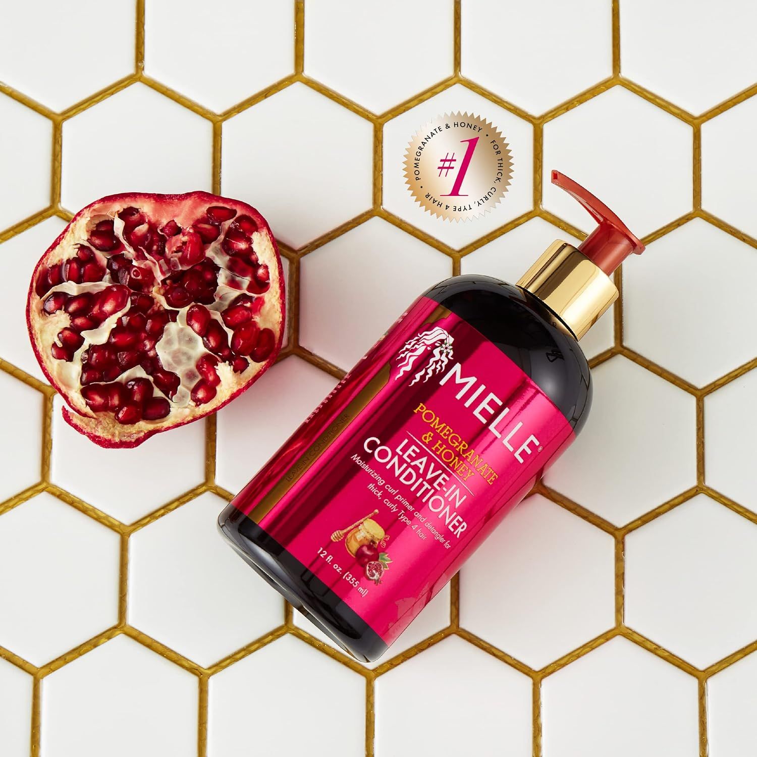 Mielle Leave-In Conditioner fles naast een halve granaatappel.