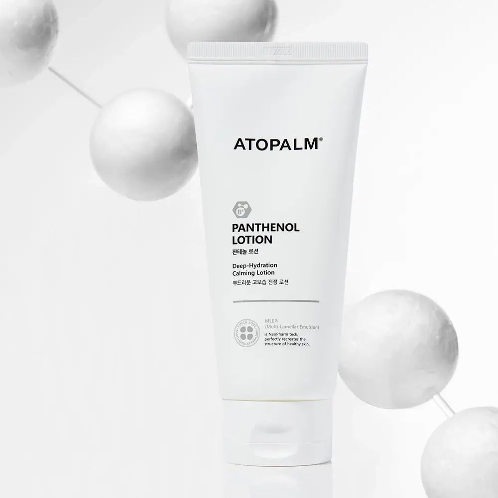 Tube blanc ATOPALM, texte PANTENOL LOTION. Arrière-plan avec sphères blanches.