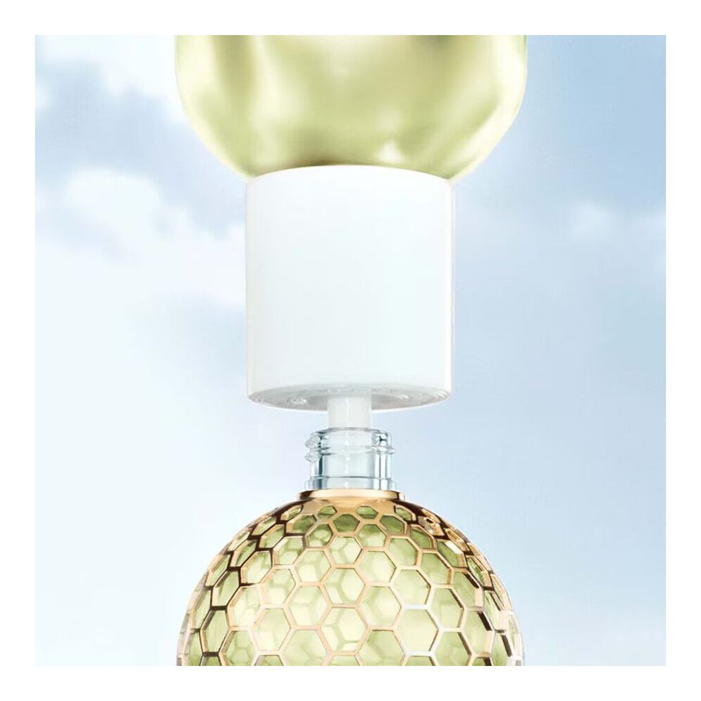 Le flacon est fermé par une partie blanche. Le flacon a un design en nid d'abeille et est en verre.