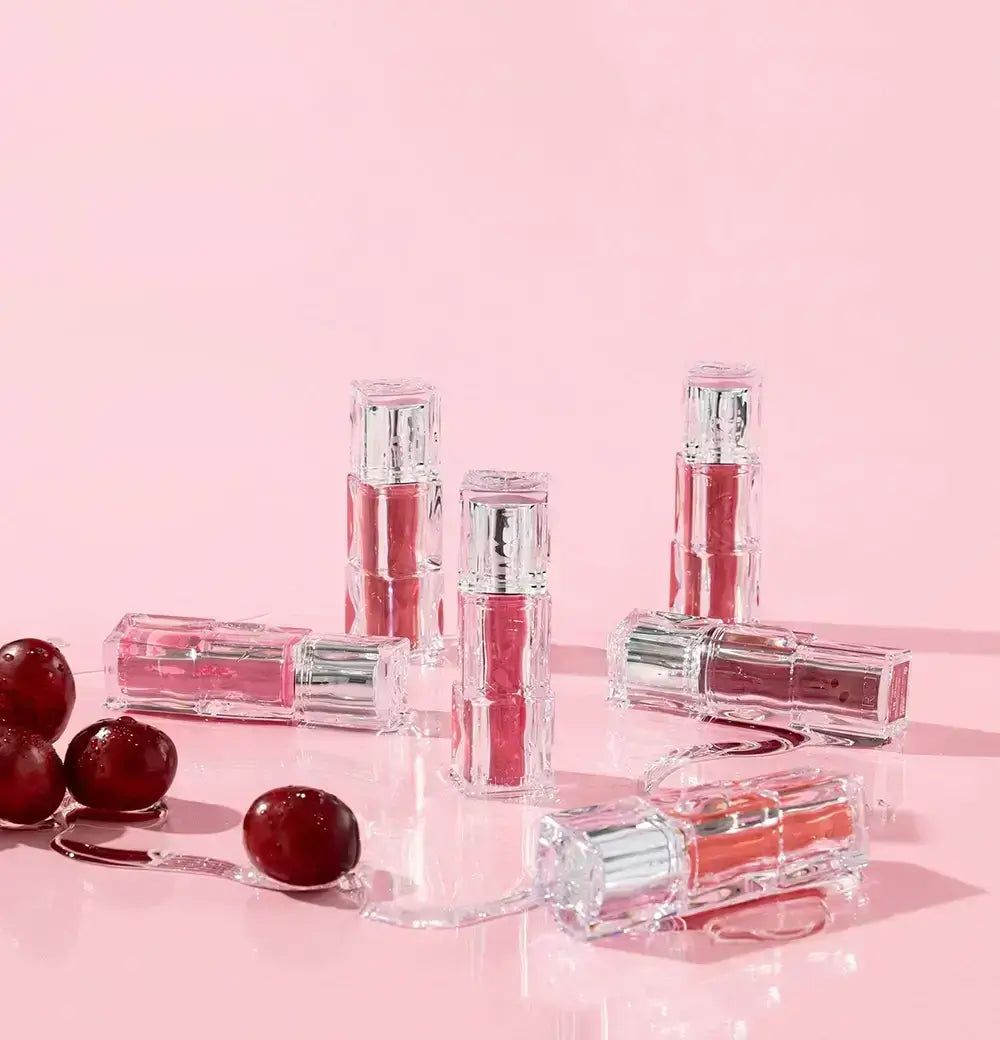 Meerdere TINTIR Waterism Glow Tints op roze achtergrond met kersen.