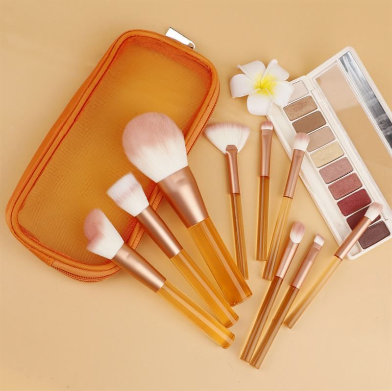 Ensemble de pinceaux de maquillage avec manches orange transparents, poils roses, dans une trousse orange. Avec palette.