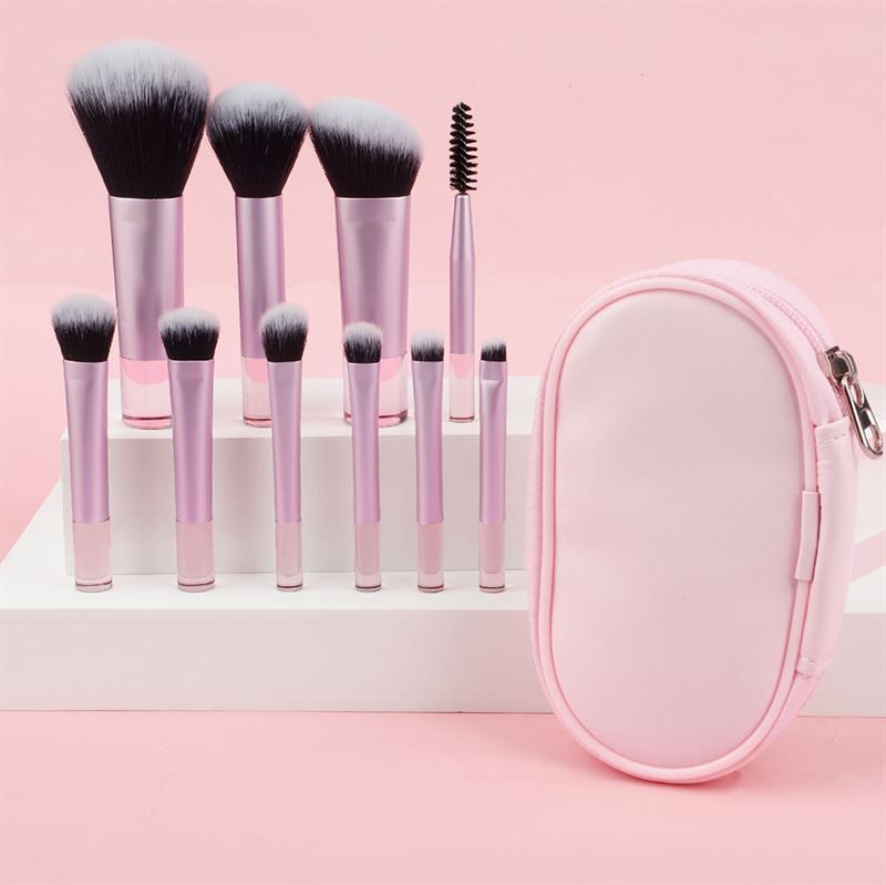Ensemble de pinceaux avec manches roses et trousse rose. Pinceaux avec poils noirs et blancs. La trousse est ovale.