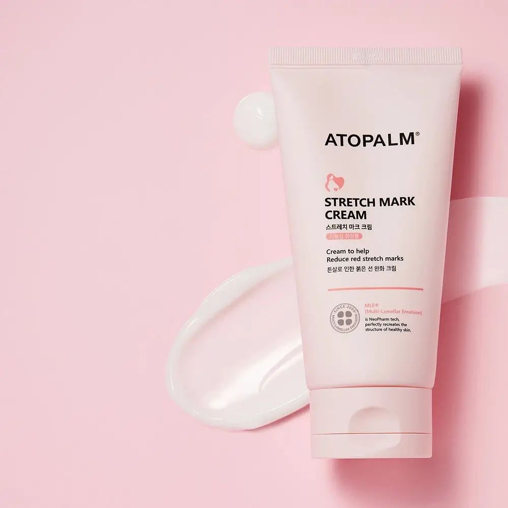 Roze ATOPALM tube en "STRETCH MARK CREAM". Crème ernaast op roze achtergrond.