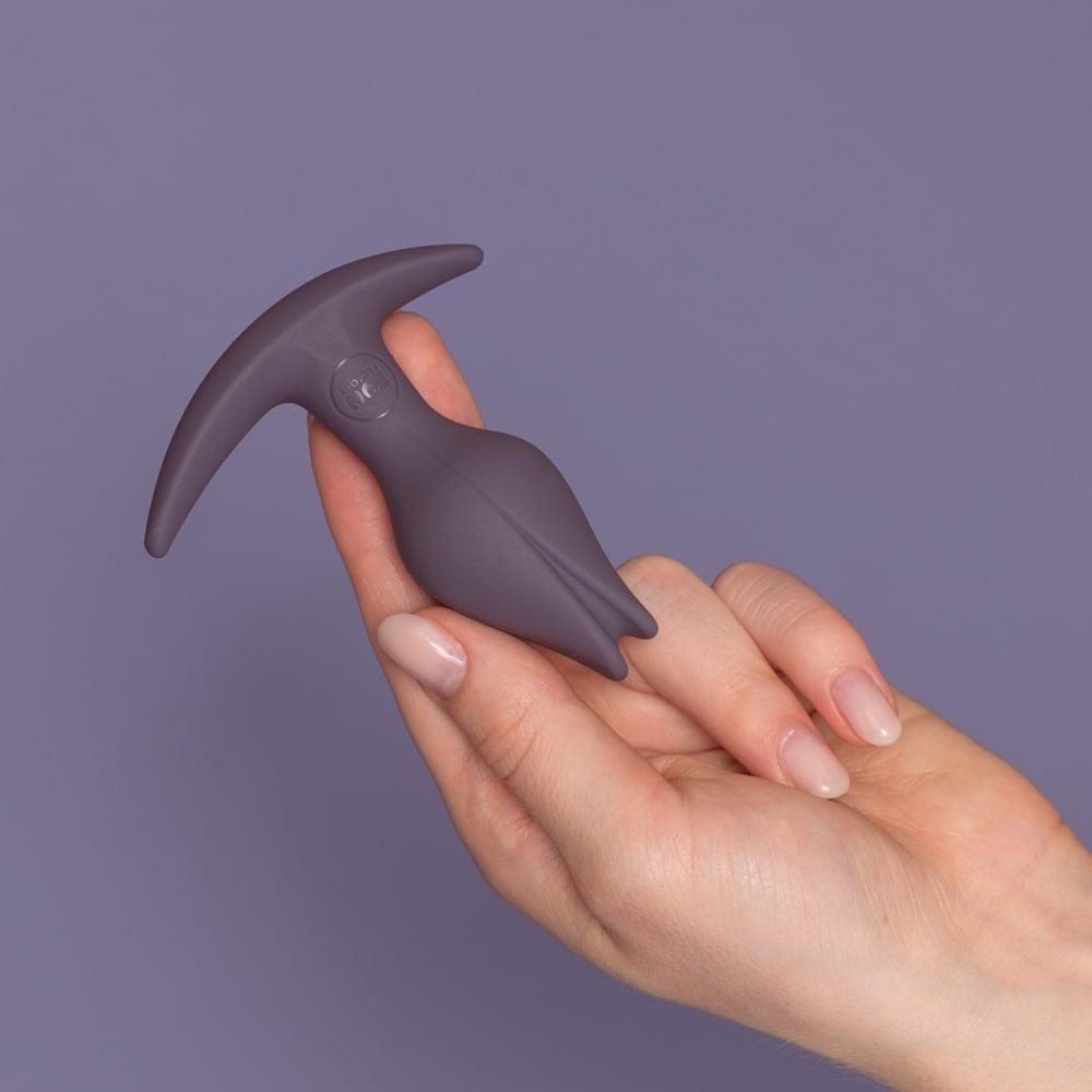 Bouchon anal gris foncé en forme de fleur, vu de côté.