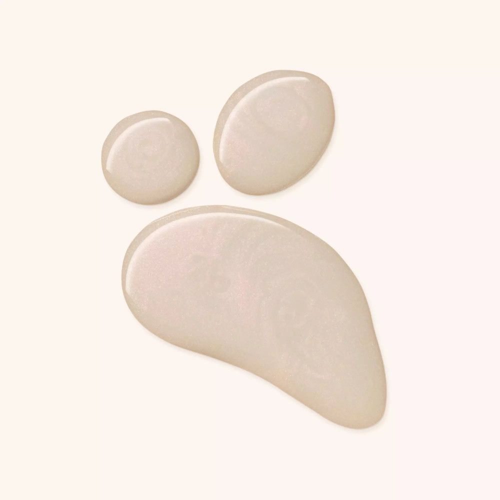 Trois gouttes de Catrice Skin Glaze Serum-Primer sur fond clair. Gouttes de différentes tailles et formes.