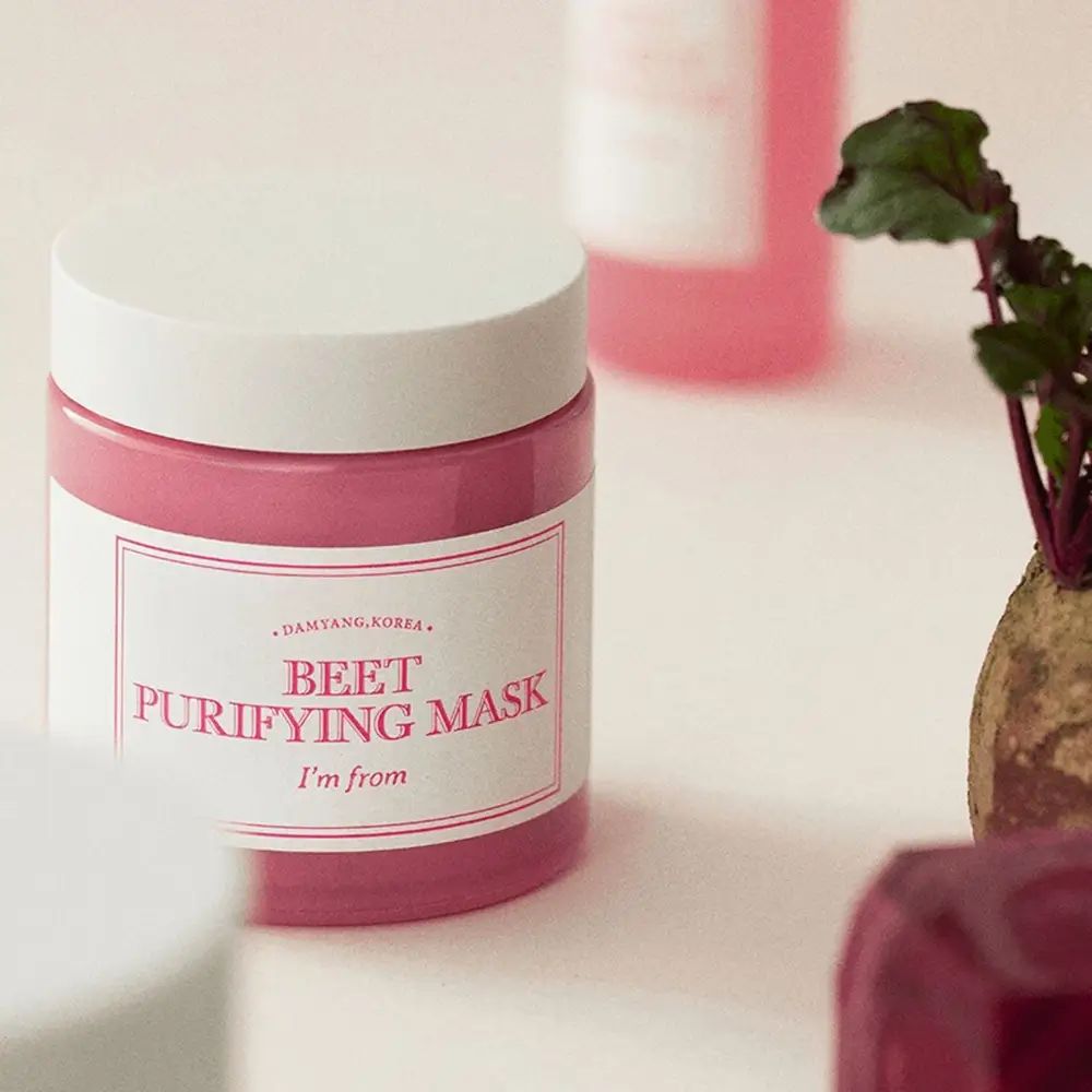 Roze gezichtsmasker in pot met witte deksel. Tekst: BEET PURIFYING MASK, I'm from. Rode biet op de achtergrond.