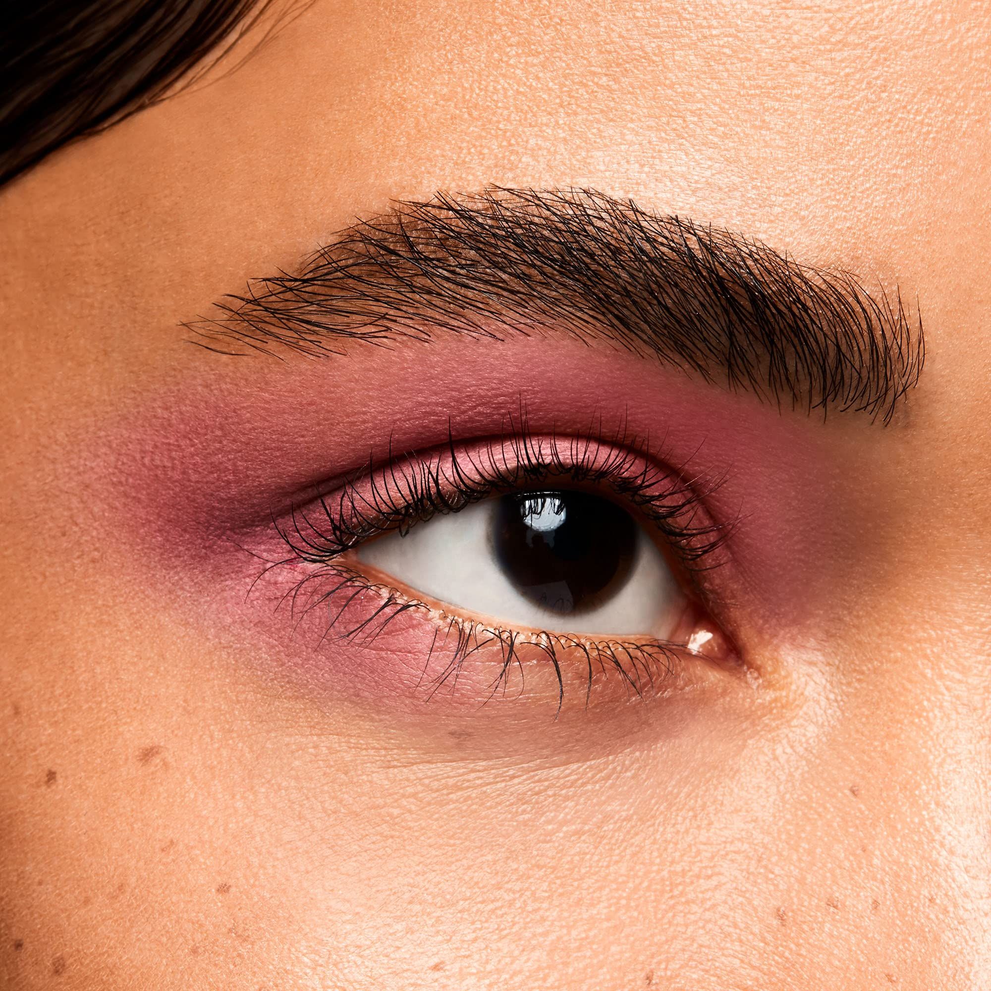 Œil avec fard à paupières rose. Sourcil brun, cils. Gros plan.