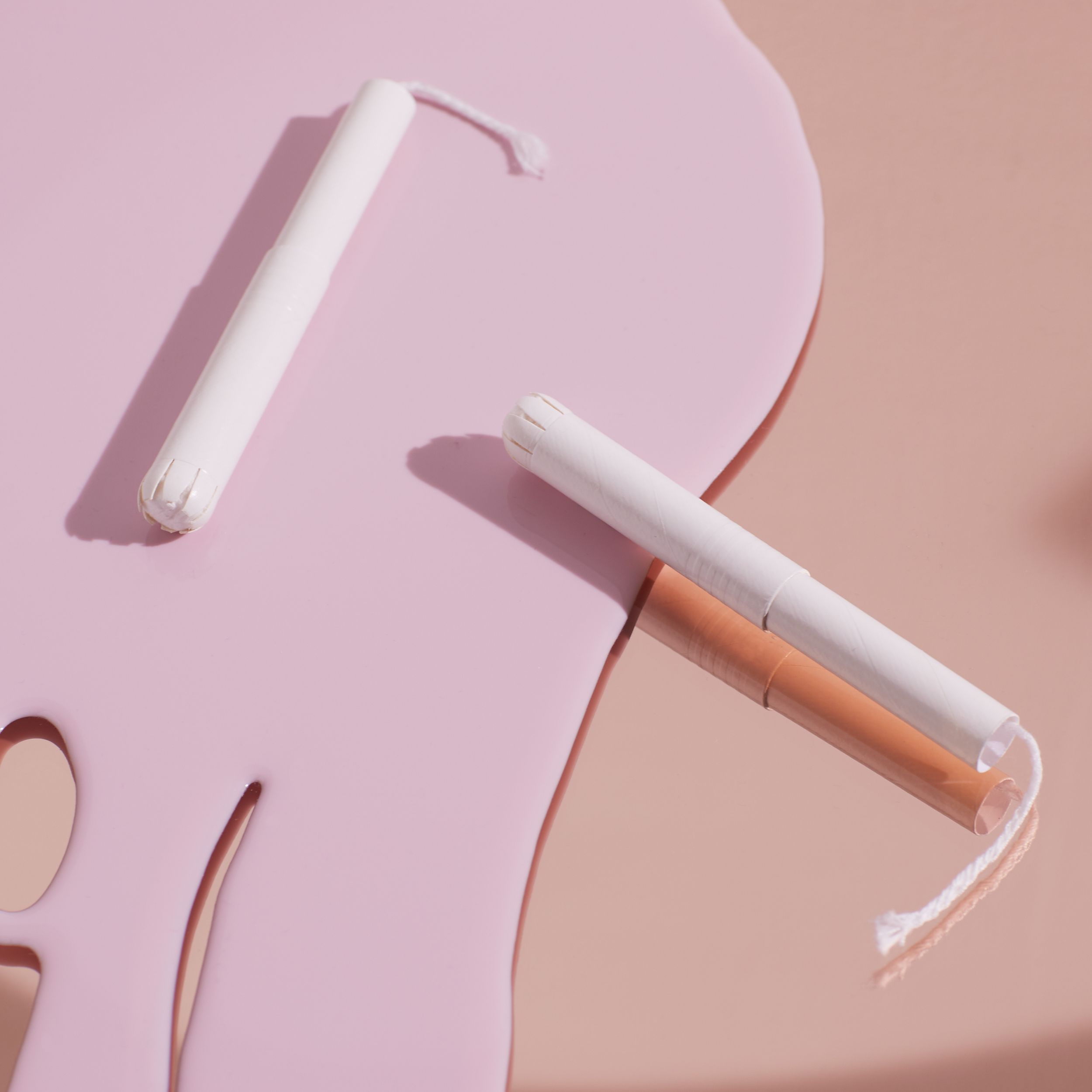 Deux tampons avec applicateur sur fond rose. Tampon blanc avec fil. L'applicateur est visible.
