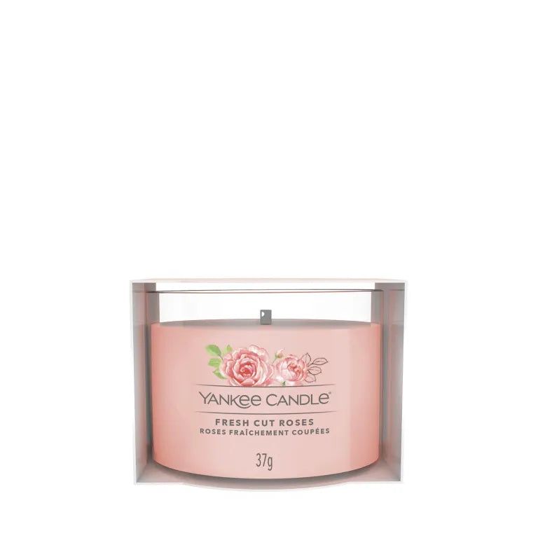 Bougie rose dans un emballage transparent. Inscription: Yankee Candle, Fresh Cut Roses, 37g. Illustration de roses.