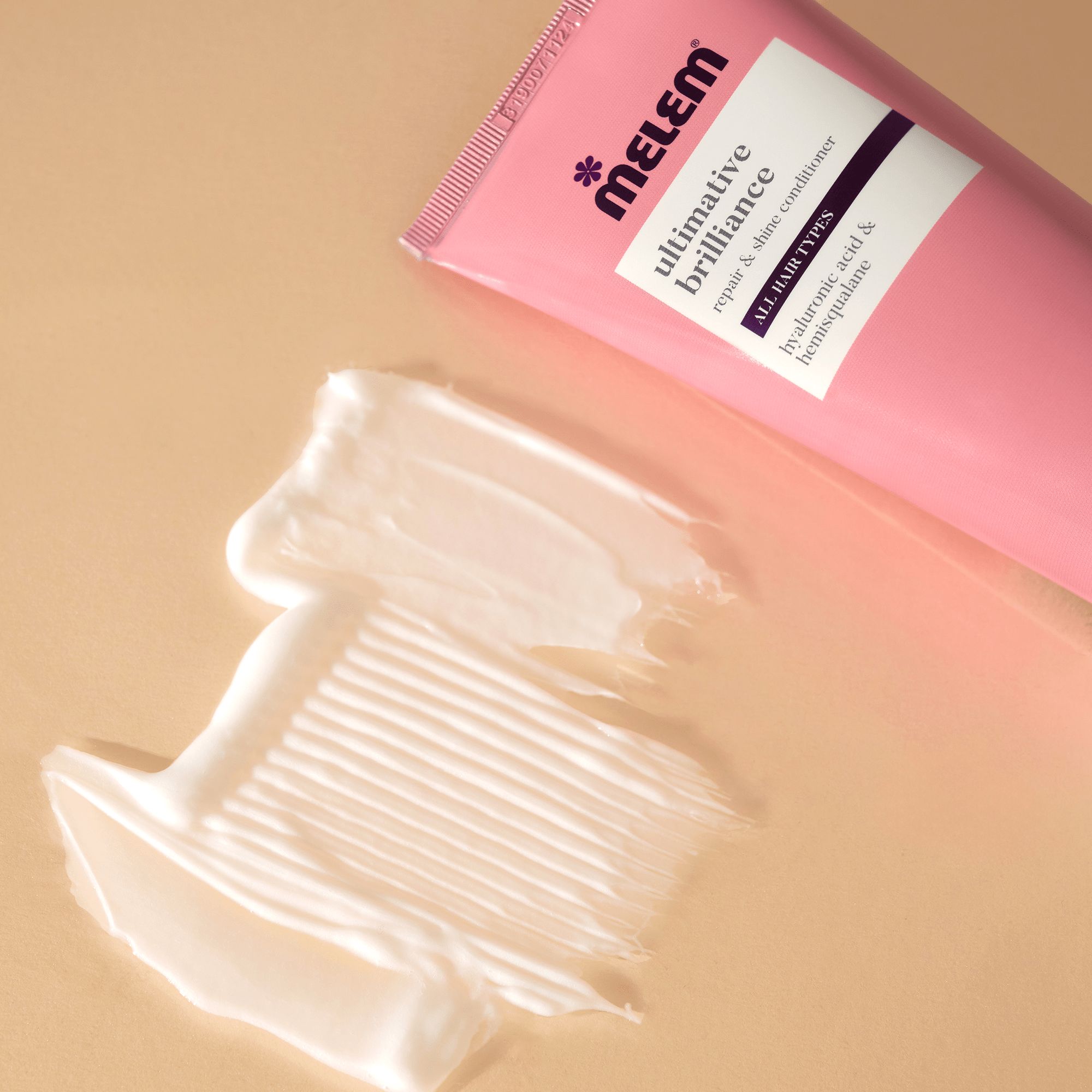 Tube rose et produit sur une surface. Inscription: Melem, ultimative Brilliance, Repair & Shine Conditioner. Pour tous types de cheveux.
