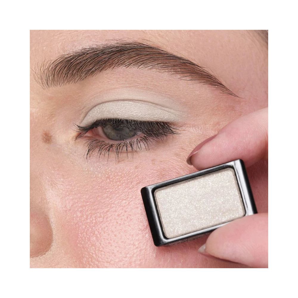 Œil avec fard à paupières appliqué. Boîtier de fard à paupières rectangulaire tenu en main.