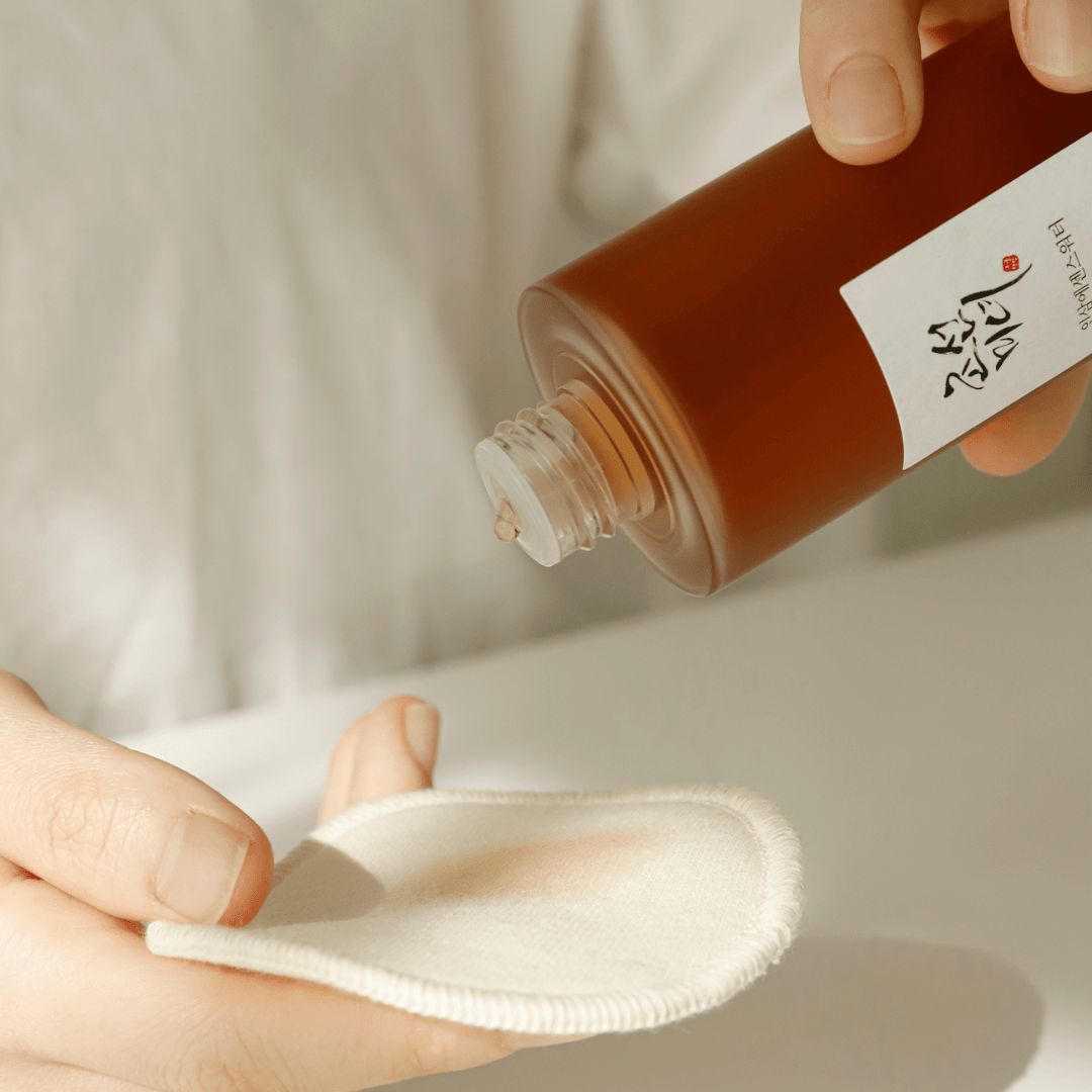 Mains tenant un flacon et un coton. Liquide versé sur le coton. Flacon avec étiquette.