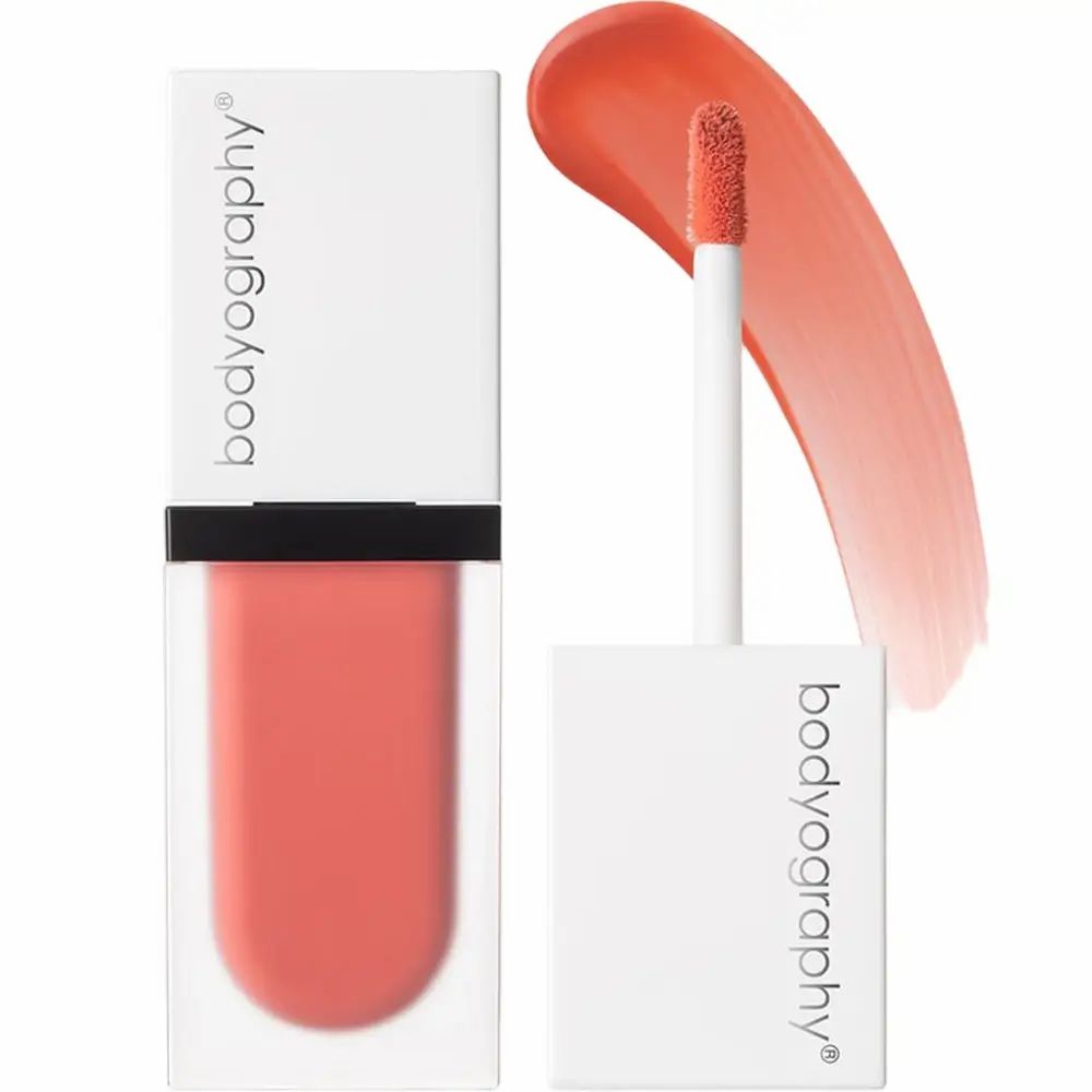 Vloeibare blush-container met applicator en kleurstaal. Merk BODYOGRAPHY is zichtbaar. Perzikkleur.