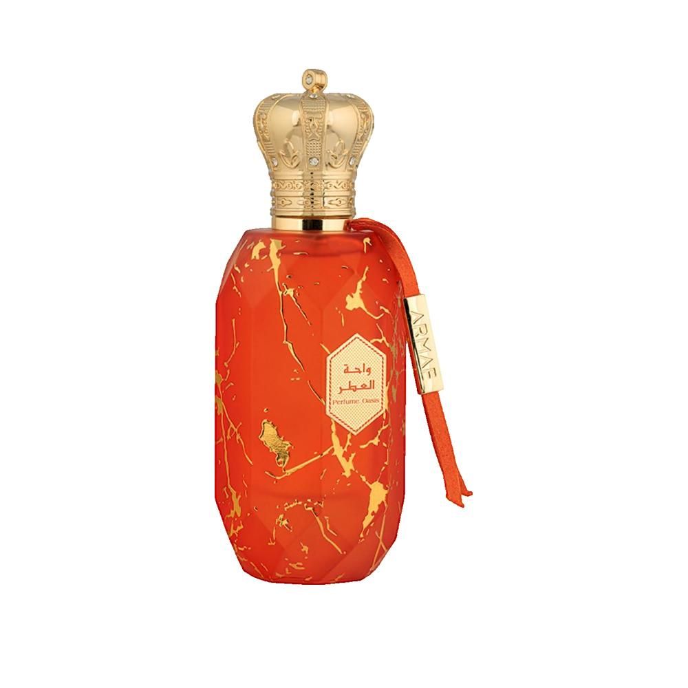 Flacon de parfum avec couronne dorée et motif marbré orange. Ruban rouge avec nom de la marque. Caractères arabes.