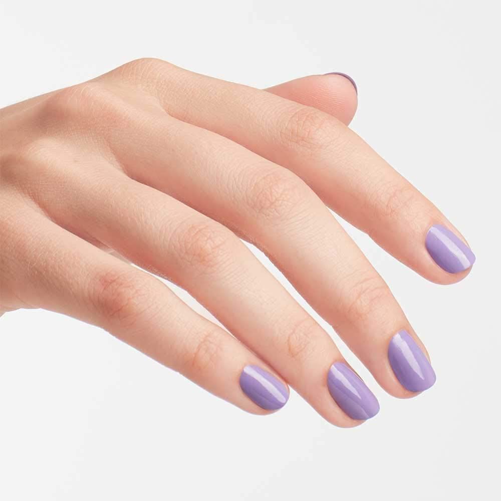 Main avec ongles vernis en lilas clair. Les ongles sont de forme ovale.