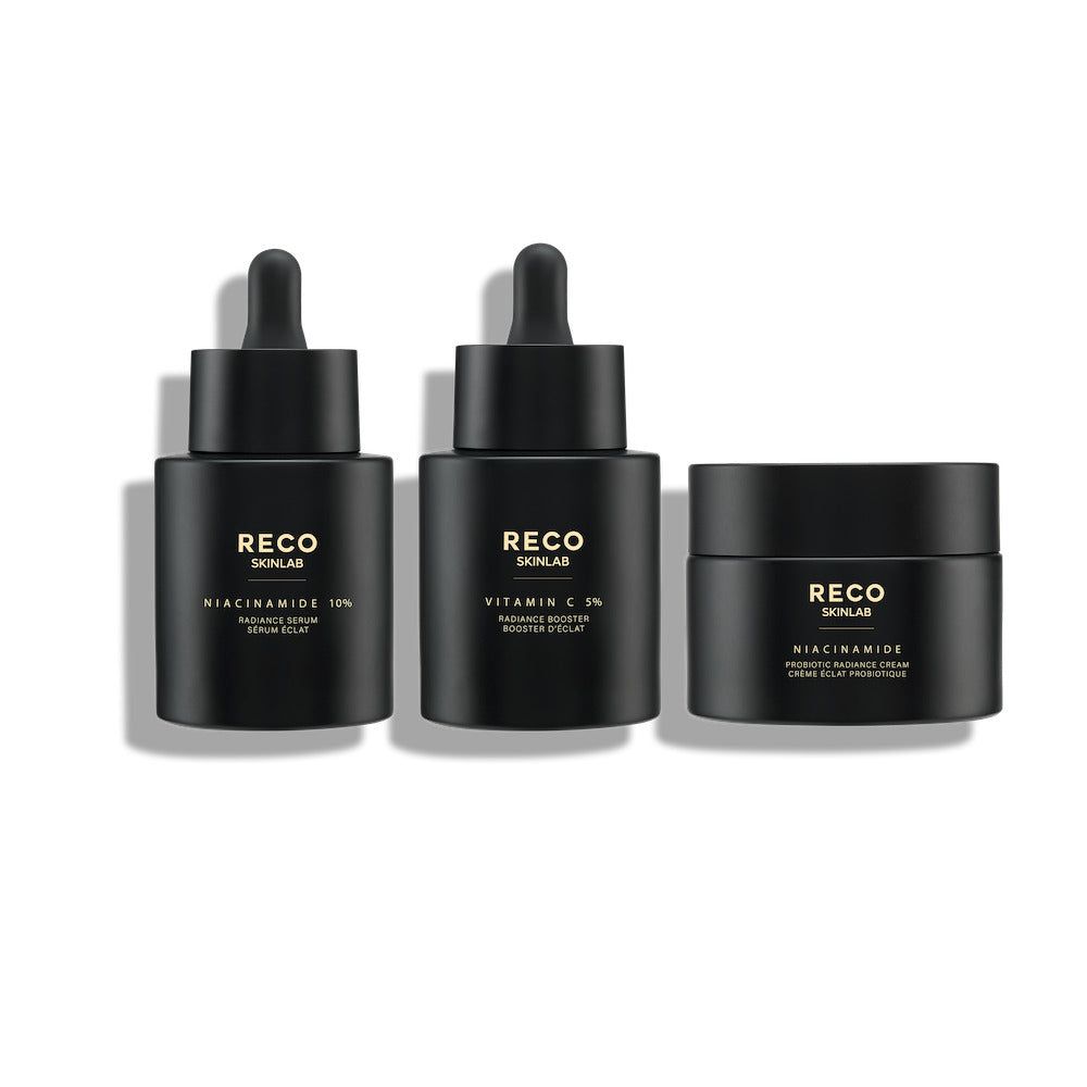 Drie zwarte flacons en een pot. Opschrift: RECO SKINLAB. Producten: Niacinamide 10%, Vitamine C 5%, Niacinamide. Druppelaars en deksels.
