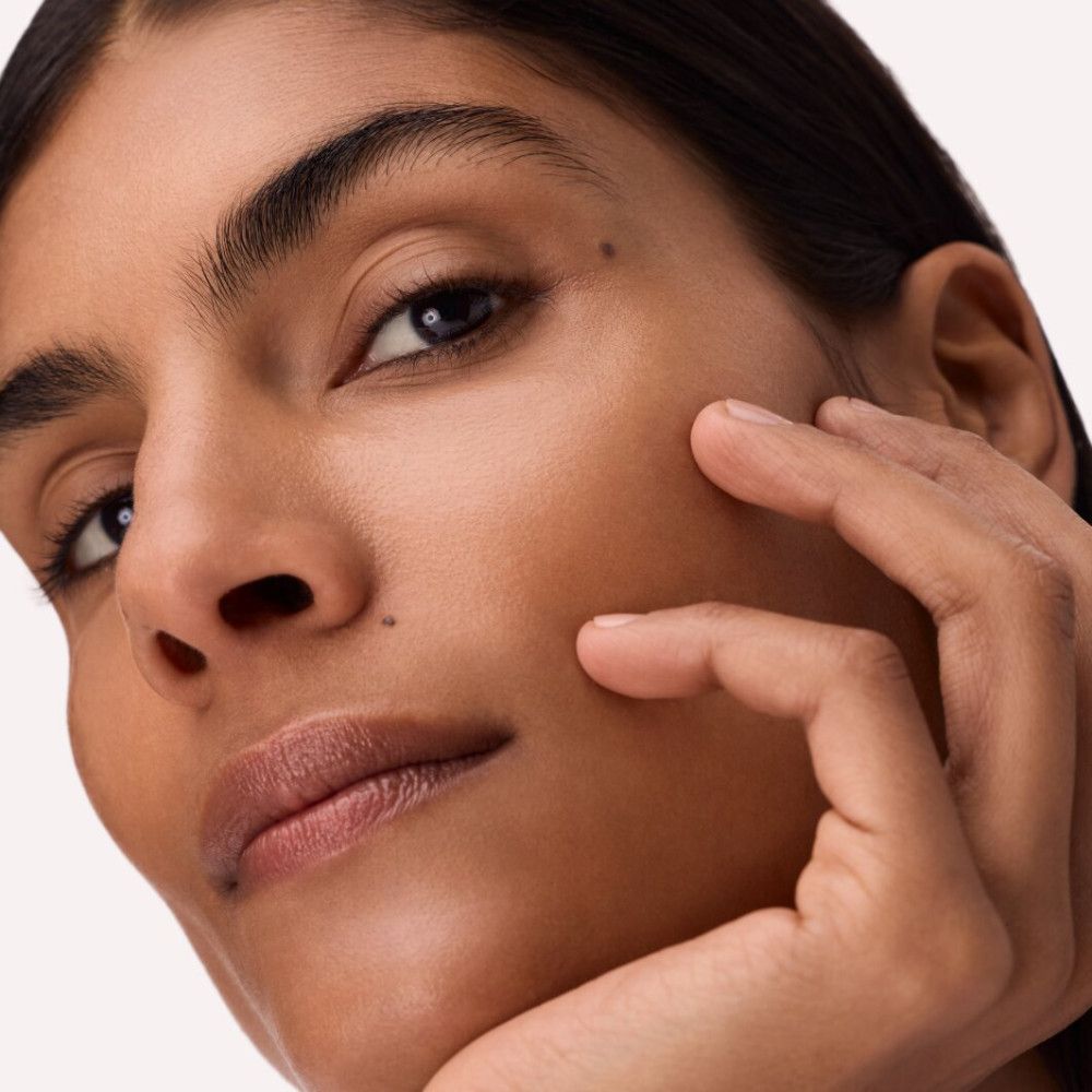 Gros plan d'un visage. La personne touche son visage avec sa main. Aucun produit visible.