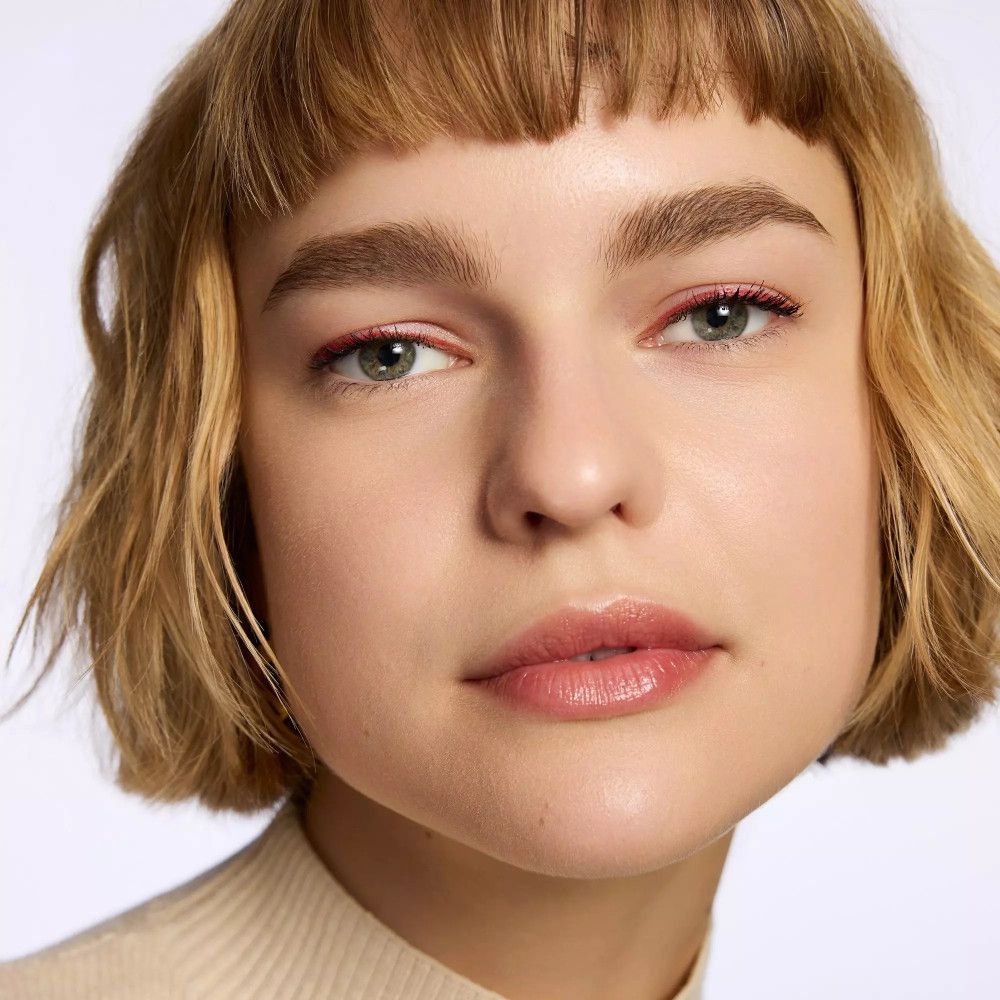 Portrait d'une femme avec un trait d'eyeliner rouge. Cheveux blonds courts.
