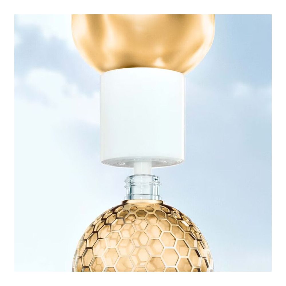 Gouden fles met honingraatpatroon. Witte sluiting wordt geplaatst. Glazen fles.